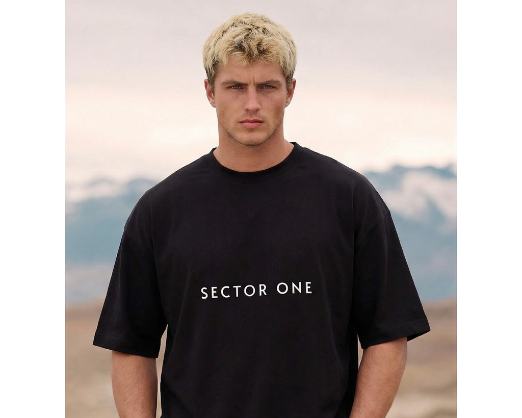 Man wearing a black 'Sector One' t-shirt with mountains in the background
