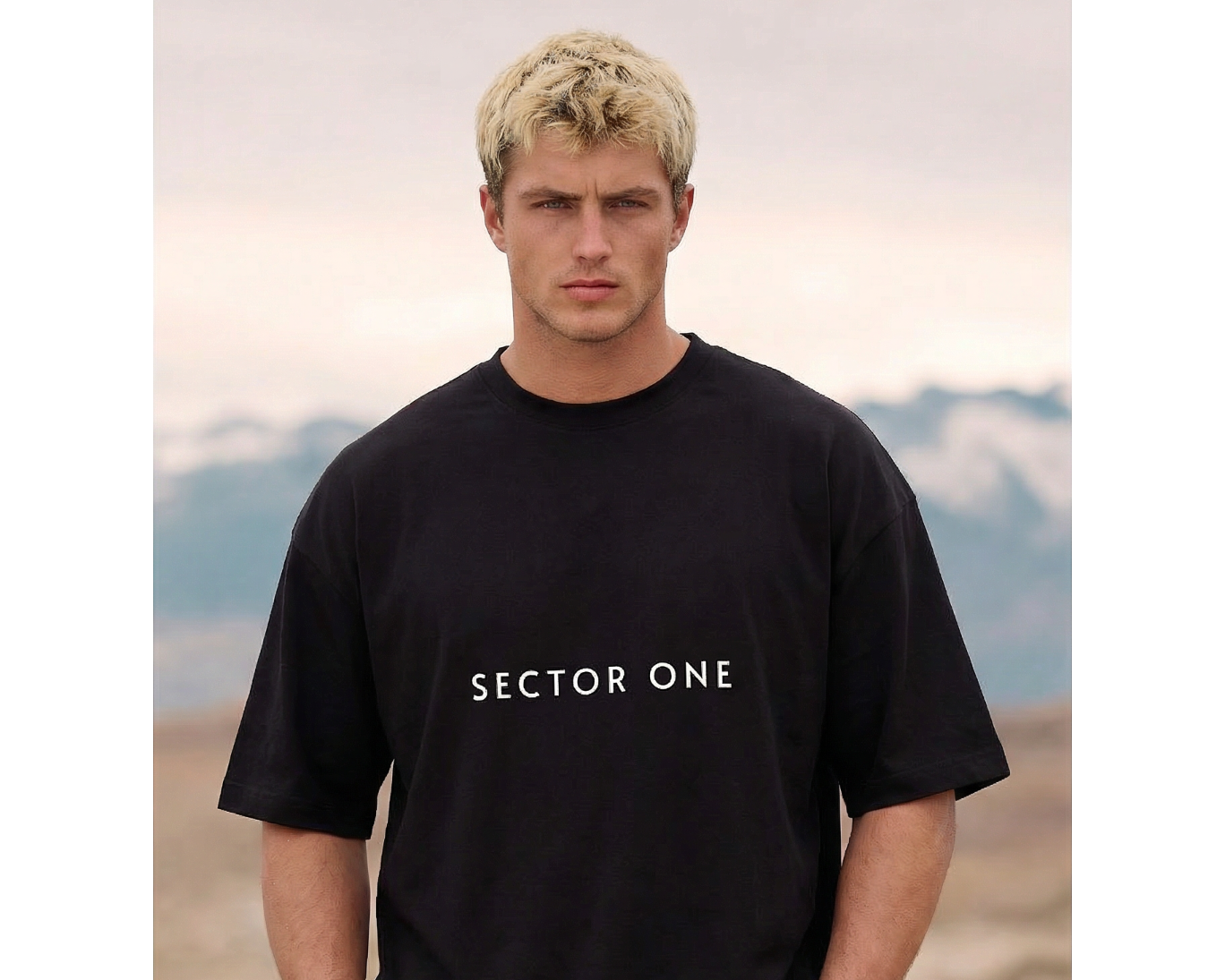 Man wearing a black 'Sector One' t-shirt with mountains in the background